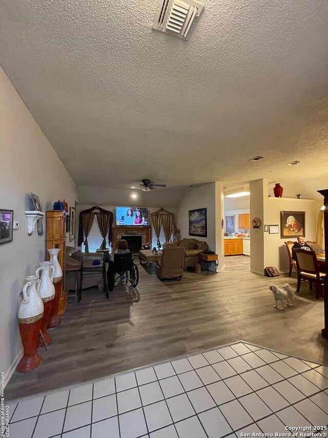 living room with a ceiling fan, a textured ceiling, and visible vents