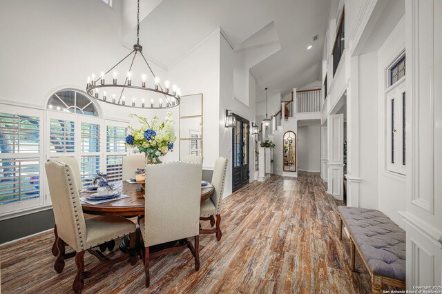 dining space featuring an inviting chandelier, wood finished floors, and high vaulted ceiling