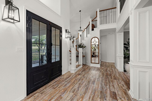 entryway with french doors, baseboards, wood finished floors, a high ceiling, and stairway