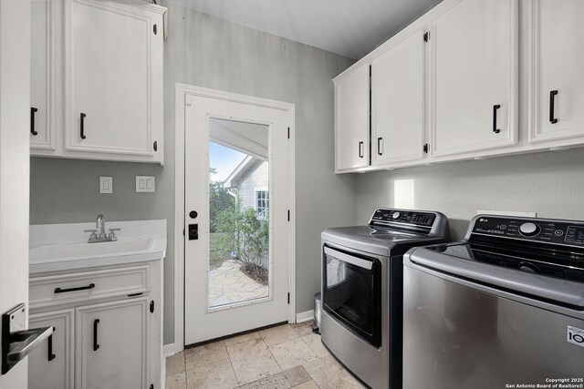 laundry room with a sink, stone tile flooring, baseboards, washer and dryer, and cabinet space