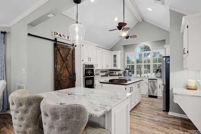 kitchen with a ceiling fan, light wood-type flooring, white cabinets, appliances with stainless steel finishes, and a kitchen island