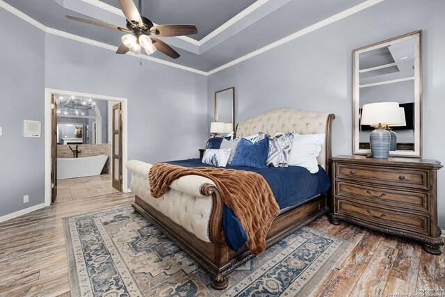 bedroom with wood finished floors, ensuite bath, crown molding, and baseboards