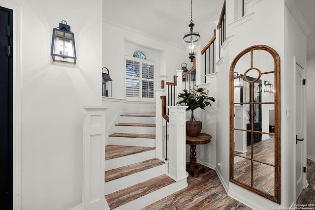 stairway featuring baseboards, ornamental molding, and wood finished floors