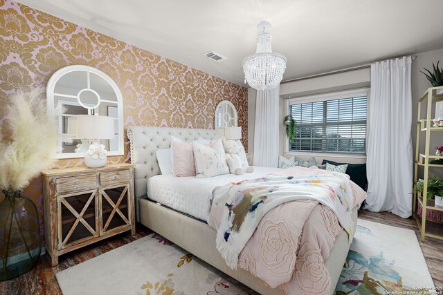 bedroom with a notable chandelier, visible vents, wood finished floors, and wallpapered walls