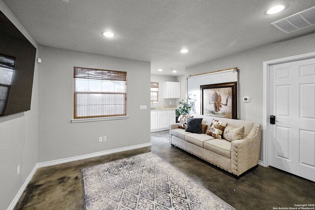 living room with concrete flooring, a textured ceiling, visible vents, and recessed lighting
