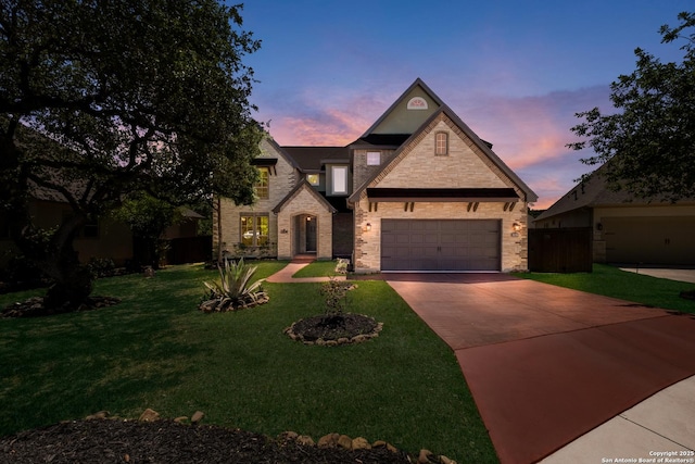 french country home with concrete driveway, a front lawn, fence, and stone siding