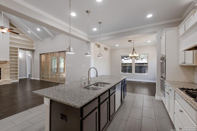 kitchen featuring a sink, open floor plan, baseboards, white cabinetry, and an island with sink