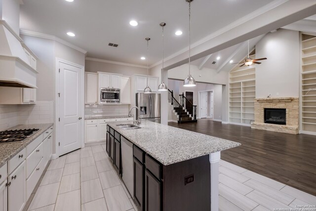 kitchen with vaulted ceiling, custom exhaust hood, a ceiling fan, a sink, and stainless steel appliances