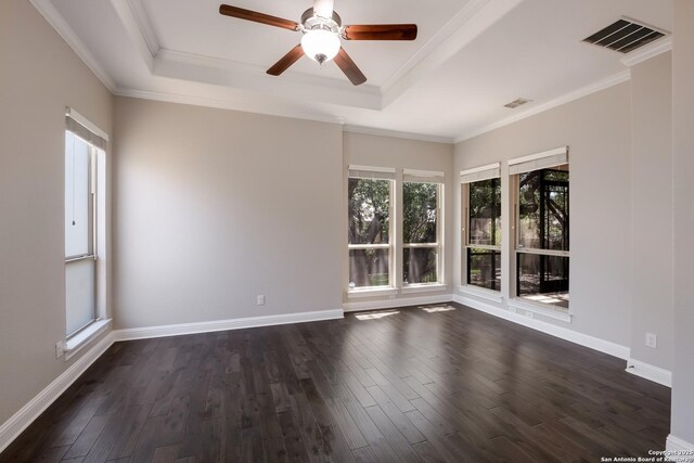 spare room featuring a ceiling fan, dark wood-type flooring, a tray ceiling, and visible vents