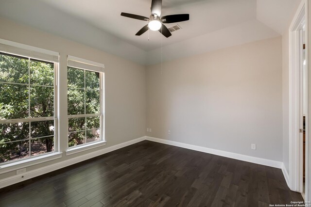 spare room with dark wood-type flooring, visible vents, baseboards, and ceiling fan