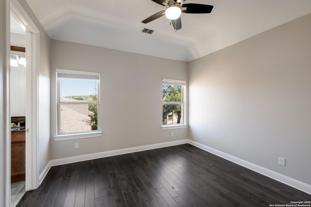 unfurnished room with dark wood-type flooring, a ceiling fan, visible vents, and vaulted ceiling