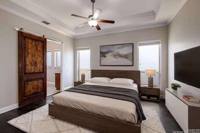 bedroom featuring a tray ceiling, dark wood-style flooring, a barn door, visible vents, and crown molding
