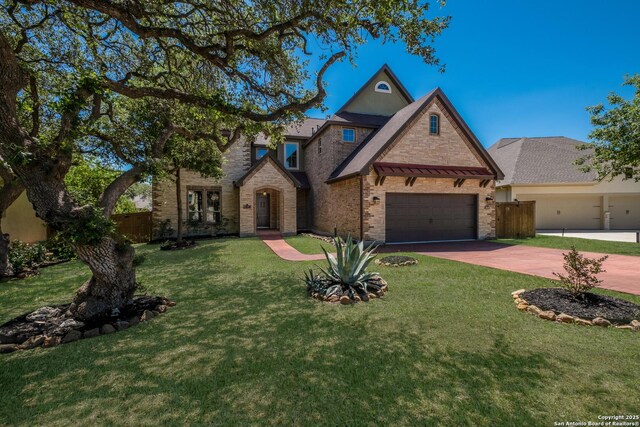 view of front of property featuring fence, a front lawn, driveway, brick siding, and a garage
