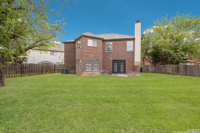 back of house featuring french doors, a lawn, a fenced backyard, and a chimney