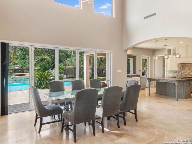 dining space featuring arched walkways, a high ceiling, and visible vents