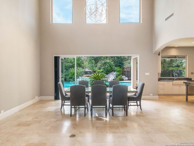 dining space with visible vents, plenty of natural light, a towering ceiling, and arched walkways