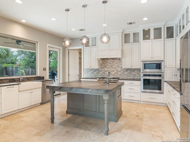 kitchen featuring tasteful backsplash, butcher block countertops, a sink, stainless steel appliances, and visible vents