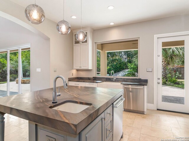 kitchen featuring recessed lighting, dark countertops, hanging light fixtures, and a sink