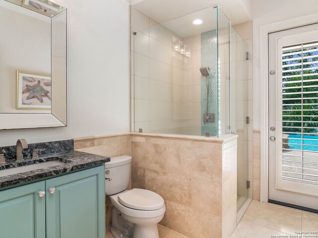 bathroom with a stall shower, vanity, tile walls, toilet, and tile patterned flooring