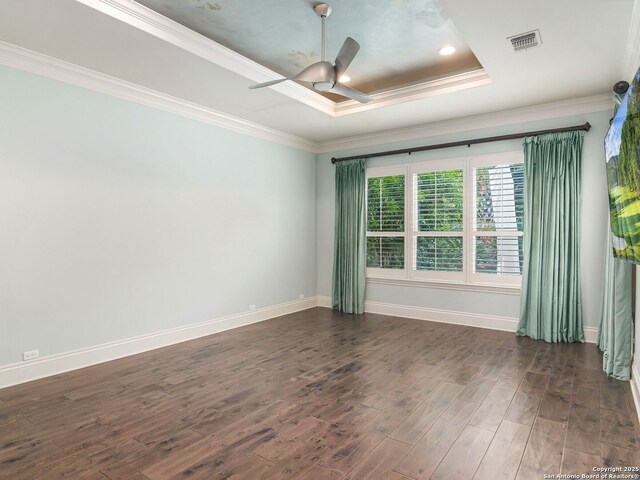 unfurnished room with dark wood-style floors, a tray ceiling, visible vents, crown molding, and baseboards