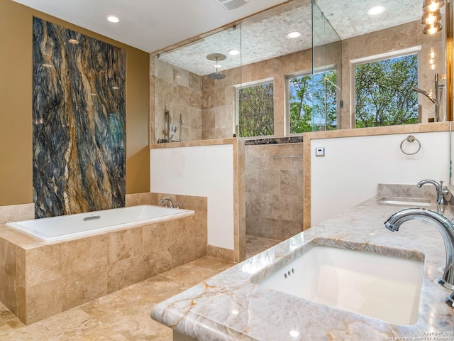 bathroom with recessed lighting, a bath, walk in shower, and a sink