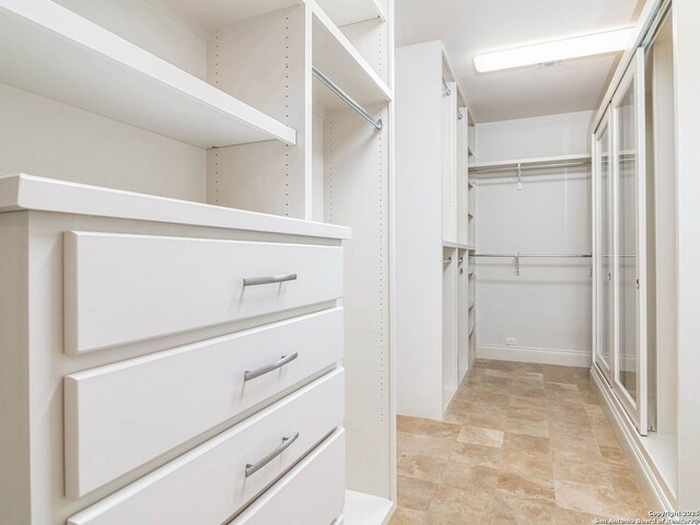 spacious closet featuring stone finish flooring