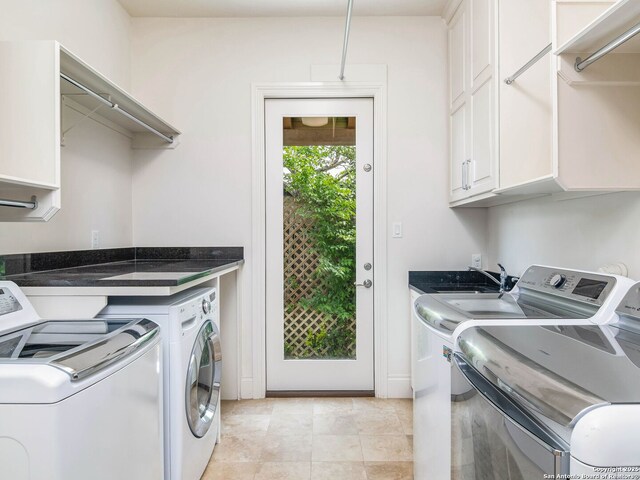 laundry area featuring independent washer and dryer, light tile patterned floors, and cabinet space