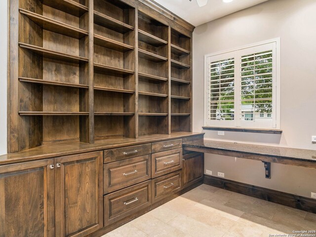 unfurnished office with built in desk and light tile patterned floors
