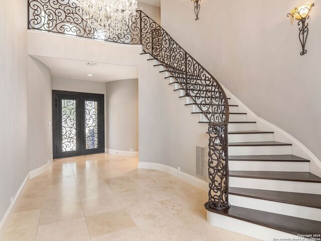 entryway with stairway, french doors, baseboards, a high ceiling, and visible vents