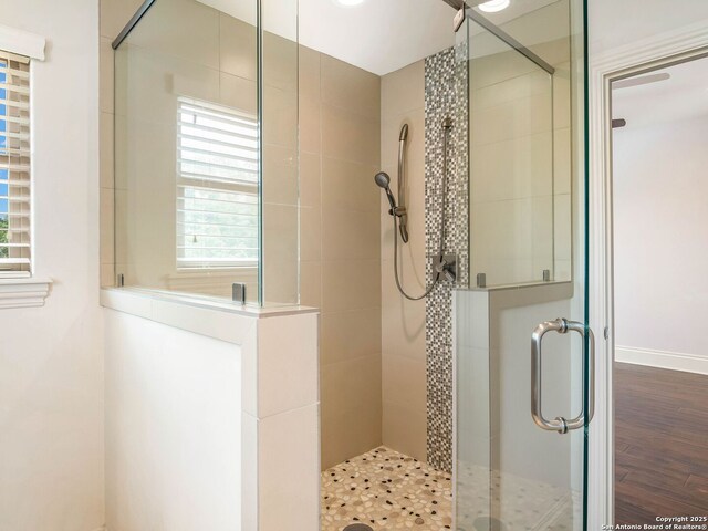 full bath featuring baseboards, wood finished floors, and a stall shower