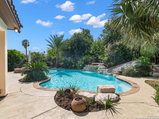 outdoor pool featuring a water slide and a patio