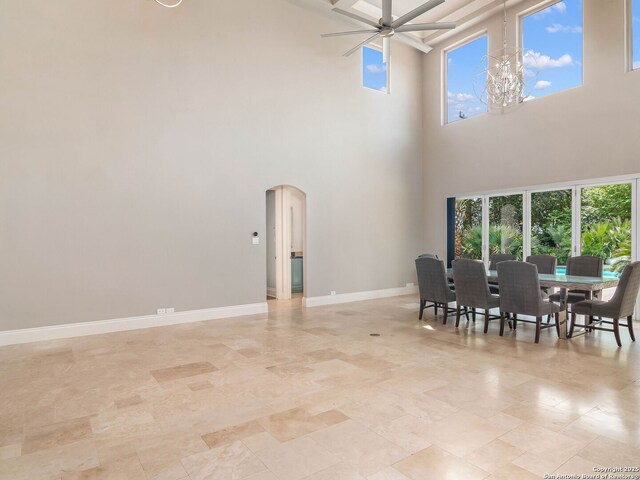 dining space with arched walkways, plenty of natural light, a ceiling fan, and a towering ceiling