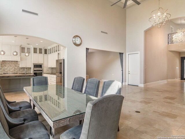 dining area with arched walkways, a high ceiling, baseboards, and visible vents