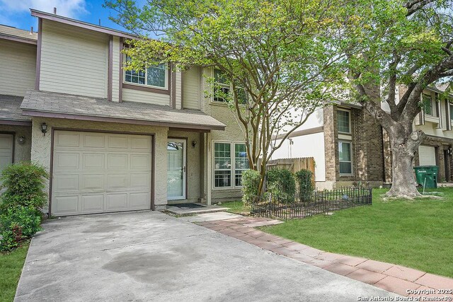 view of front facade with an attached garage, a front lawn, fence, and roof with shingles