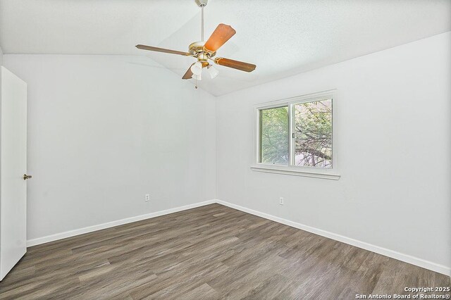 empty room featuring lofted ceiling, a ceiling fan, baseboards, and wood finished floors