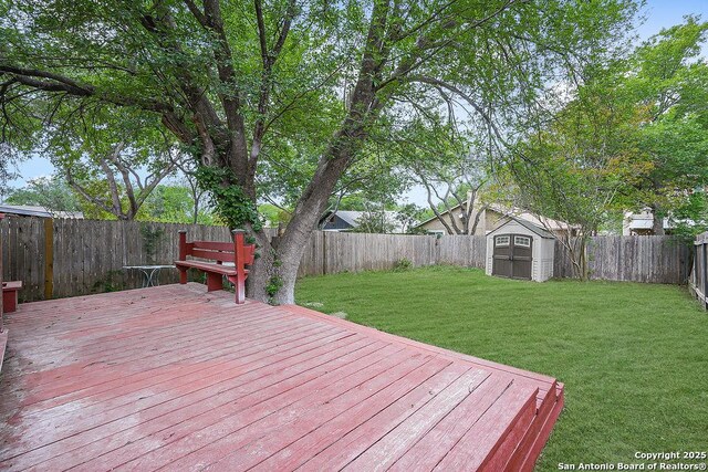 wooden terrace with an outdoor structure, a yard, a shed, and a fenced backyard