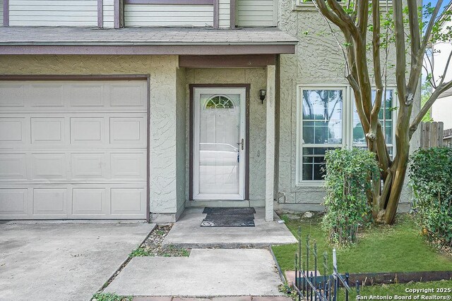 view of exterior entry with a garage and stucco siding