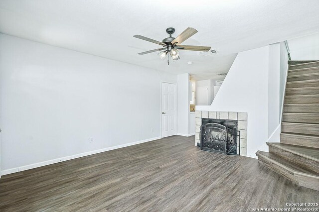 unfurnished living room featuring wood finished floors, visible vents, stairs, and ceiling fan