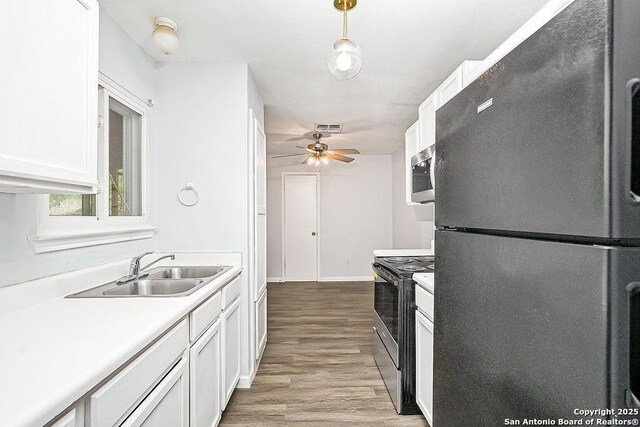 kitchen with a sink, light wood-style floors, stainless steel appliances, light countertops, and visible vents