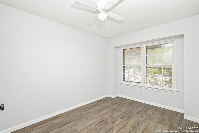 spare room with baseboards, a ceiling fan, and dark wood-style floors