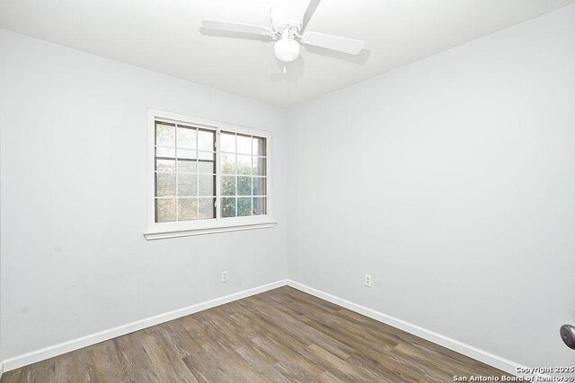 spare room featuring baseboards, ceiling fan, and dark wood-style flooring