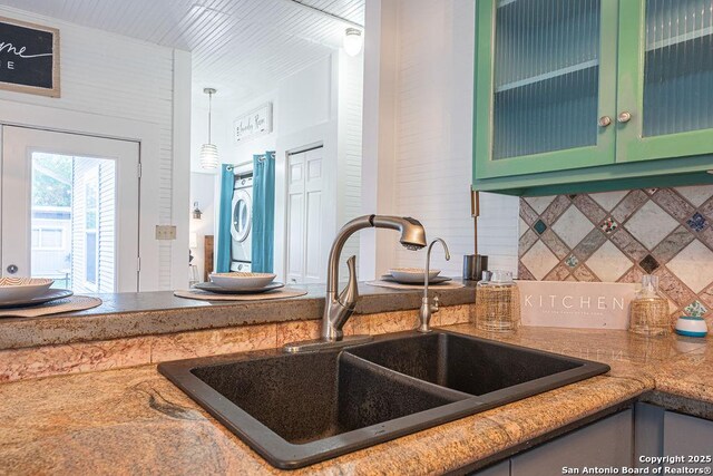 356 Kessler, New Braunfels, TX 78130 - kitchen featuring tasteful backsplash, a sink, glass insert cabinets, green cabinetry, and stacked washer and clothes dryer