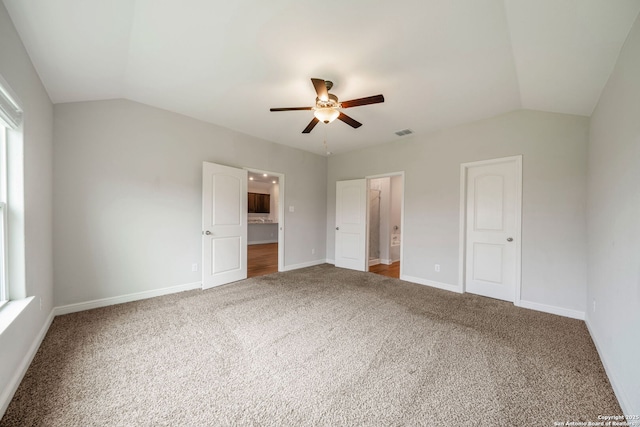 unfurnished bedroom featuring vaulted ceiling, baseboards, carpet, and ensuite bathroom
