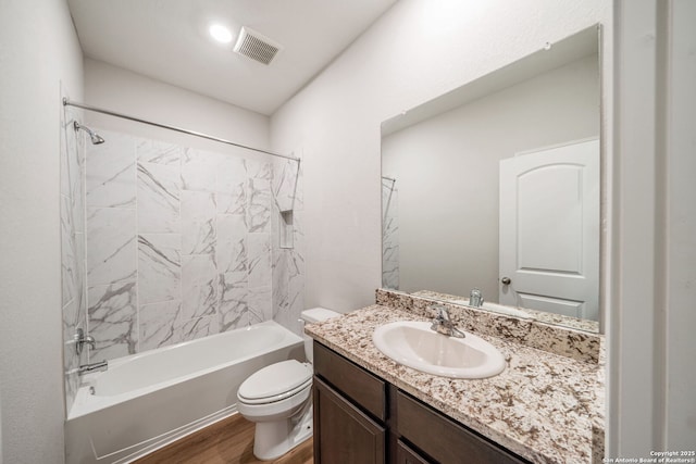 bathroom with toilet, shower / bathtub combination, visible vents, wood finished floors, and vanity