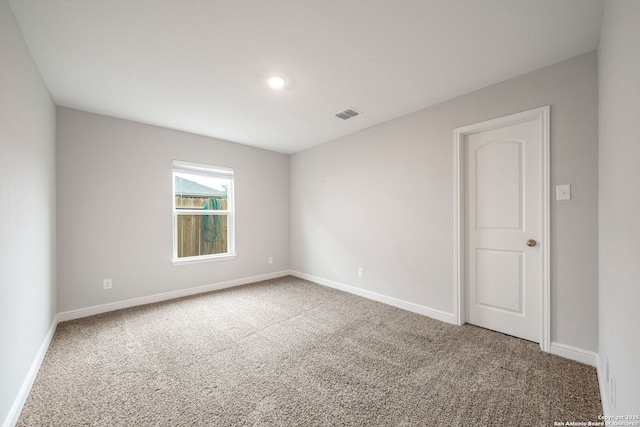 unfurnished room with carpet floors, visible vents, and baseboards