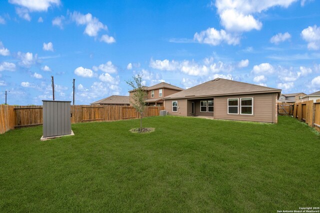 back of property featuring a yard, an outbuilding, and a fenced backyard