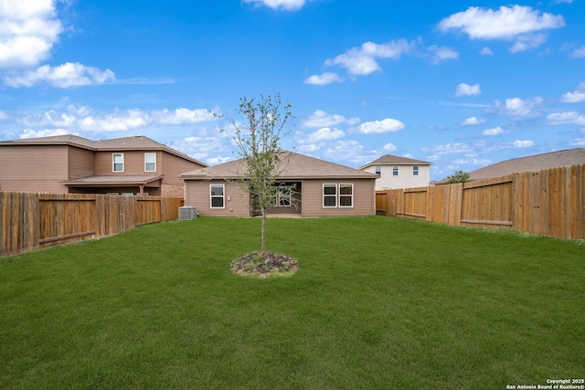 rear view of property featuring a yard, a fenced backyard, and central AC unit