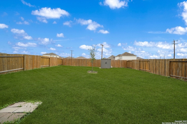view of yard featuring a fenced backyard, an outbuilding, and a shed