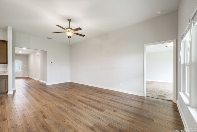unfurnished living room with baseboards, a ceiling fan, wood finished floors, and visible vents