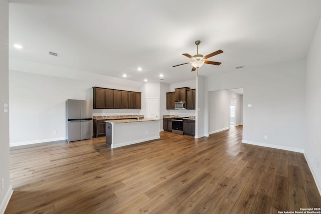 kitchen with a ceiling fan, wood finished floors, open floor plan, stainless steel appliances, and visible vents